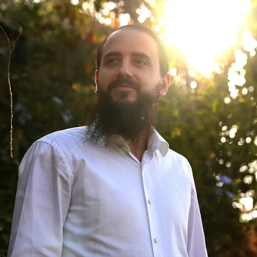 Daniel R. Chapán al aire libre, con árboles y luz de sol detrás.